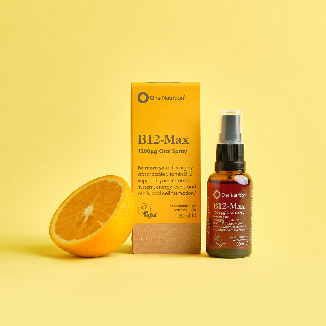 B-12 spray , product displayed beside orange slice on a yellow backdrop.