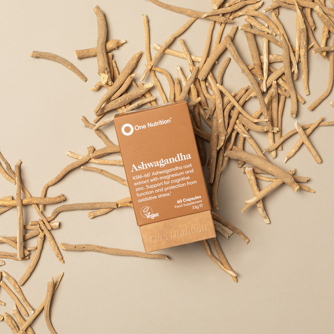 One Nutrition Ashwagandha supplement box on a beige background with dried ashwagandha roots.
